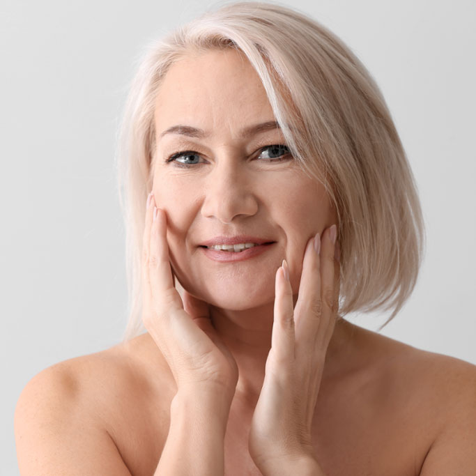 older woman touching her face and looking at camera