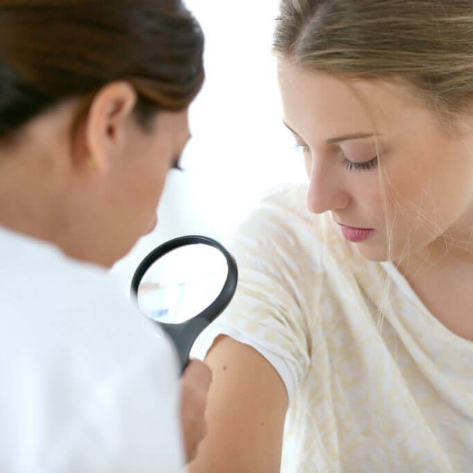 doctor diagnosing skin cancer on patient's arm in Fort Worth, TX